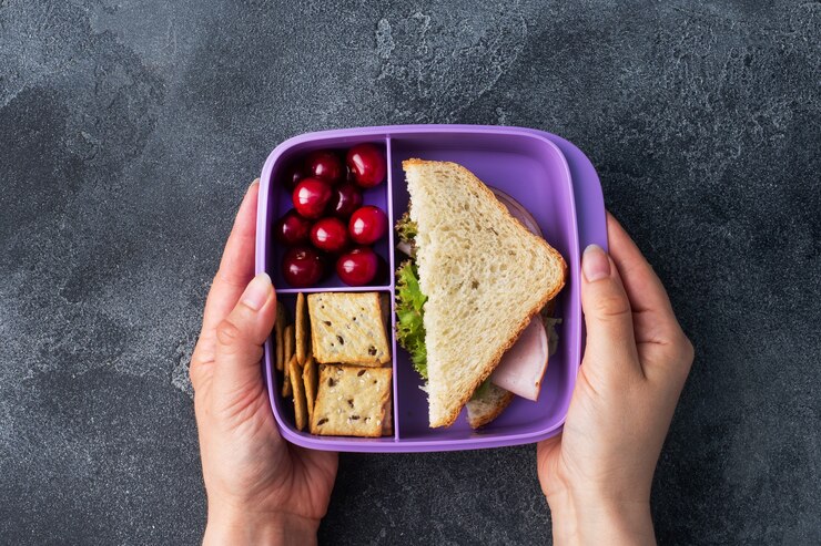 Delicioso sándwich saludable en lonchera, galletas y cerezas. Lleve el almuerzo a la escuela oa la oficina.
