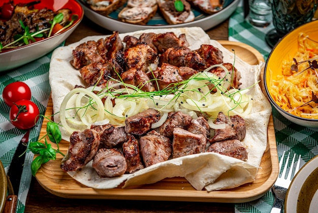 Delicioso shashlik de cerdo a la parrilla sobre mesa de madera