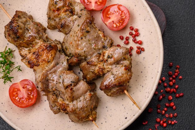 Delicioso shish kebab frito de pollo o carne de cerdo con especias saladas y hierbas sobre un fondo de hormigón oscuro