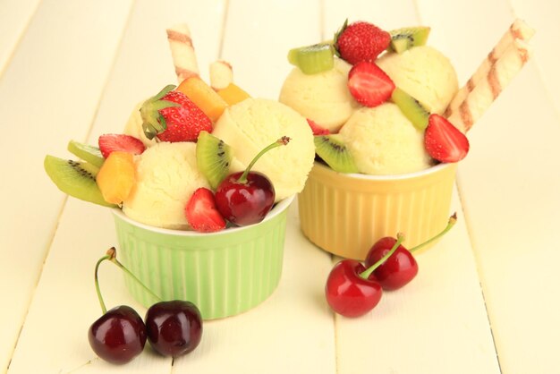 Delicioso sorvete com frutas e bagas em tigela na mesa de madeira