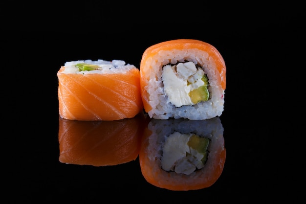 Foto delicioso sushi roll de california sobre un fondo negro con reflejo