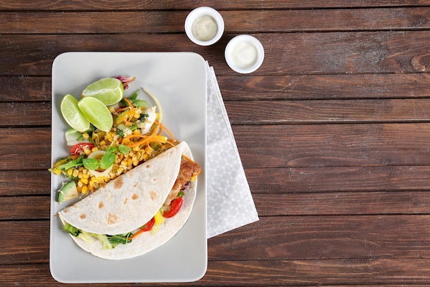 Delicioso taco de pescado servido en un plato blanco sobre una mesa de madera