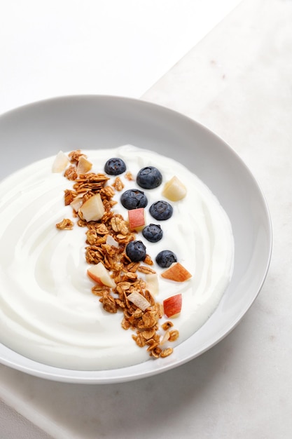 Delicioso tazón de desayuno saludable con yogur blanco arándanos frescos con granola o muesli