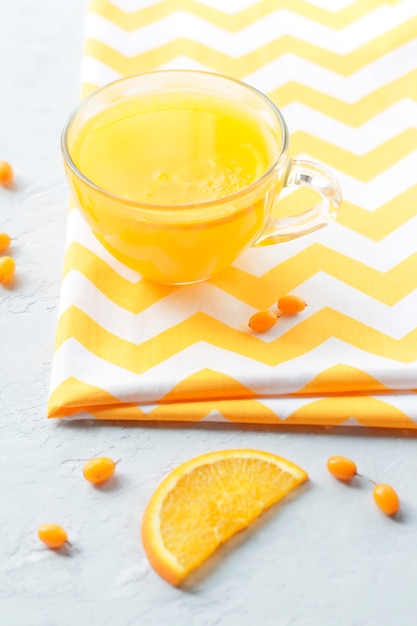 Delicioso té de espino amarillo con naranja en una taza transparente. Estilo de vida, salud, vitamina.