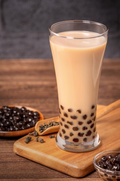 Delicioso té con leche de burbujas con bola de perla de tapioca en vidrio sobre mesa de madera y fondo de ladrillo gris oscuro comida y bebida popular en Taiwán cerca