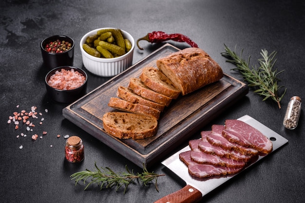 Delicioso tocino fresco en rodajas con pan y verduras sobre un fondo de hormigón oscuro