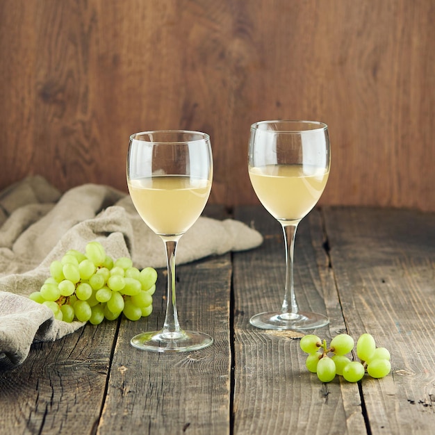 Delicioso vinho branco em copos brilhantes e uvas na mesa