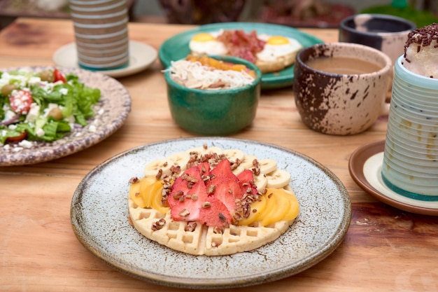 Foto delicioso waffle com morango e pêssego na mesa de madeira