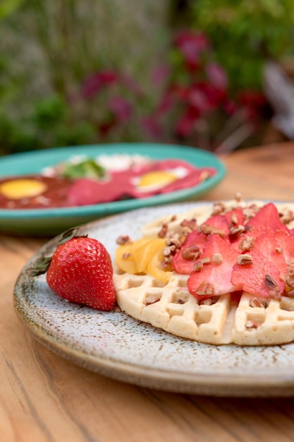 Foto delicioso waffle com morango e pêssego na mesa de madeira