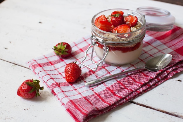 Delicioso yogur con fresas maduras frescas y cuchara en la toalla de cocina