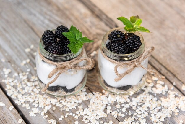 Delicioso yogur natural con moras, frambuesas y hojas de menta. En tarros de cristal.