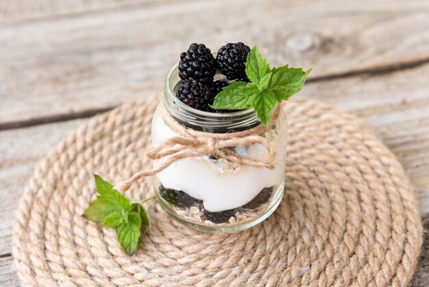 Foto delicioso yogur natural con moras y hojas de menta. al aire libre. en frascos de vidrio.