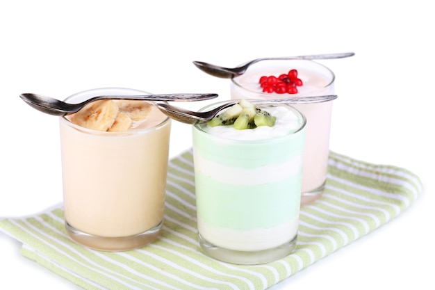 Delicioso yogur con sabores de frutas en vasos en servilleta aislado en blanco