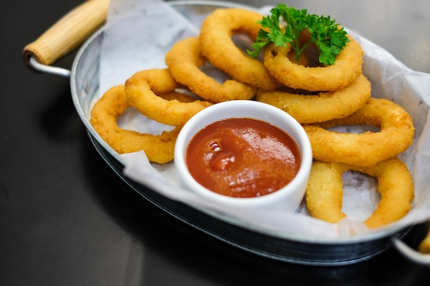 Los deliciosos aros de cebolla con salsa de tomate sirven en un tazón de metal