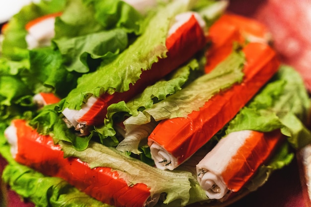 Deliciosos bastões de caranguejo recheados com ervas de peixe e molho em um prato com verde