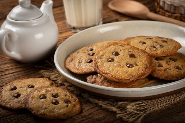 Deliciosos biscoitos de chocolate com copo de leite na mesa de madeira