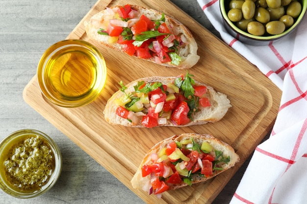 Deliciosos bocadillos bruschetta en mesa con textura gris