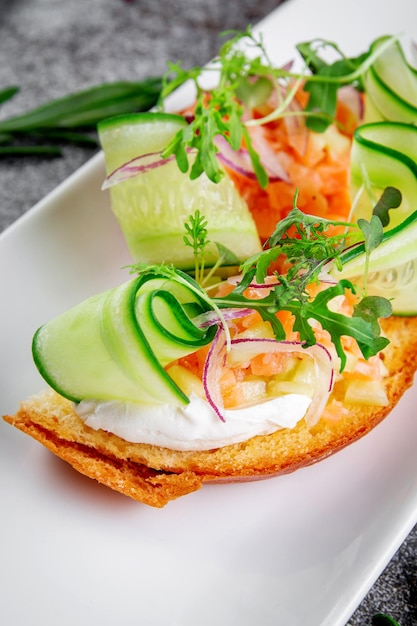 Deliciosos bocadillos Bruschetta con rodajas de salmón pepino fresco aros de cebolla roja y rúcula Crutones tostados con mariscos y lechuga