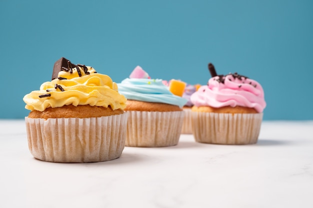 Deliciosos bolinhos caseiros com creme colorido e cobertura com doces e biscoitos de chocolate