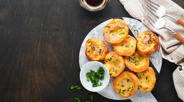 Deliciosos bolinhos de ovo com cebola verde bacon queijo e tomate na placa de madeira no antigo fundo rústico de madeira saudável café da manhã com alto teor de proteína e baixo teor de carboidratos comida caseira