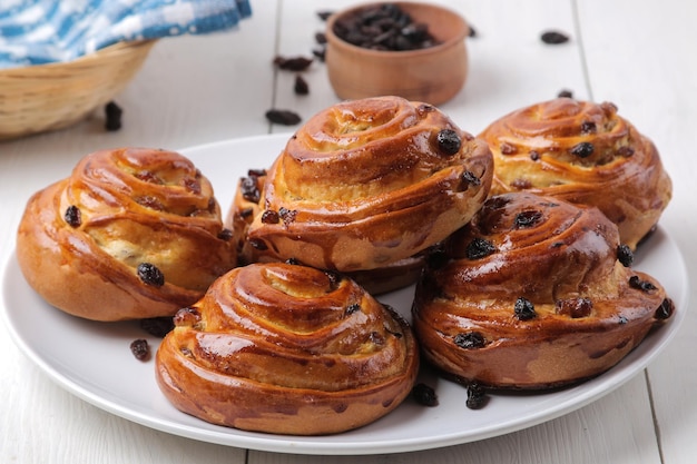 Deliciosos bollos con pasas en un plato sobre una mesa de madera blanca. panadería fresca. desayuno. pan de molde.