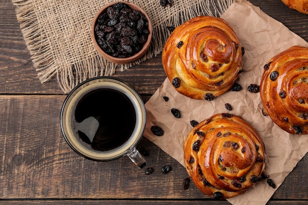 Deliciosos bollos con pasas y una taza de café en una mesa de madera marrón. panadería fresca. desayuno. pan de molde. vista superior