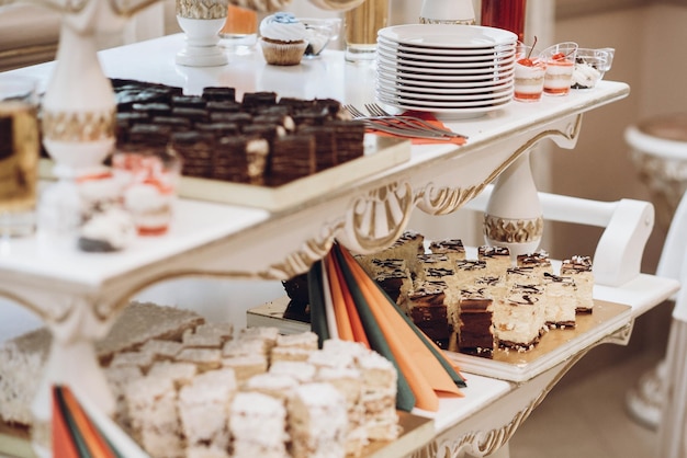 Deliciosos bolos, cupcakes e sobremesas doces na mesa na recepção do casamento no restaurante, catering de luxo, festa de natal, barra de chocolate de casamento