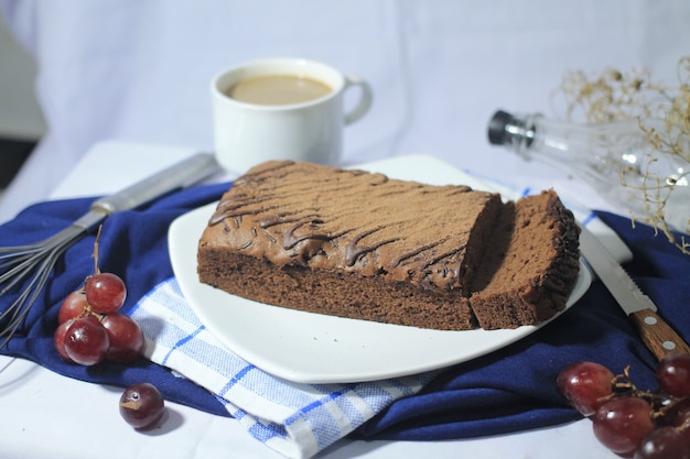 Deliciosos brownies de chocolate en un plato blanco con un vaso de uva de café y un cuchillo alrededor