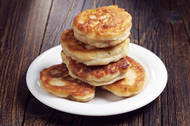 Deliciosos buñuelos caseros en plato blanco sobre mesa de madera oscura.