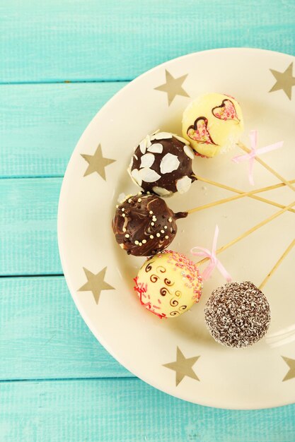 Deliciosos cake pops en un plato, en una mesa de madera