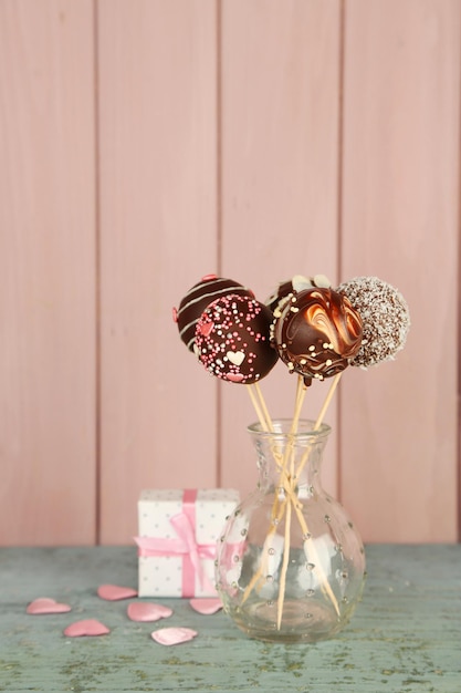 Deliciosos cake pops y regalo sobre fondo de madera