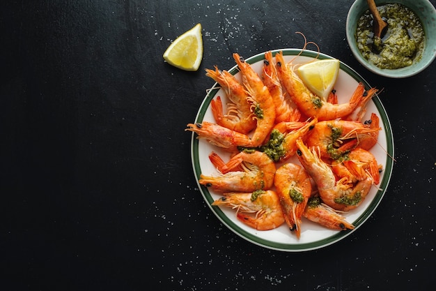 Foto deliciosos camarones con especias y salsa en un plato sobre una superficie oscura