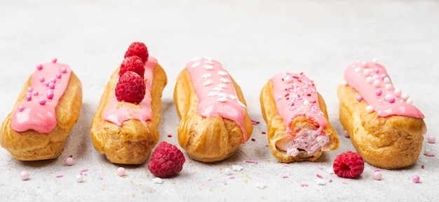 Deliciosos canutillos rosados glaseados con crema, frambuesa y chispas de azúcar. Formato de pancarta.