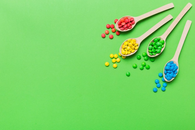 Deliciosos caramelos dulces coloridos en cuchara sobre fondo de color Vista superior de decoración de confitería con espacio de copia