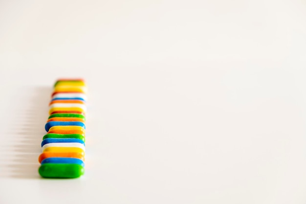Deliciosos caramelos de regaliz dulce de color en cápsulas o pastillas sobre un fondo blanco formando una línea vertical con espacio para copiar texto