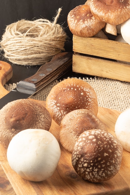 Deliciosos champiñones (shiitake y champiñón) en tabla de cortar y caja.