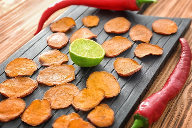 Deliciosos chips de batata en tablero de madera