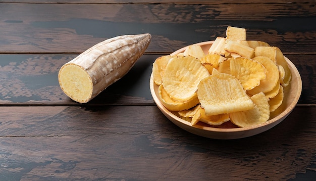 deliciosos chips de mandioca e um pouco de mandioca em fundo escuro de madeira com espaço de cópia