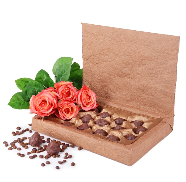 Deliciosos chocolates en caja con flores aislado en blanco