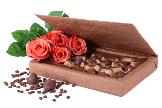 Deliciosos chocolates en caja con flores aislado en blanco