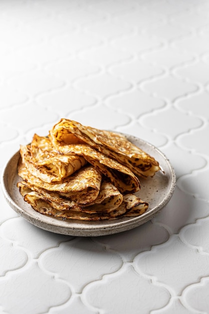 Deliciosos crepes caseros en placa de cerámica sobre fondo de azulejo blanco para maslenitsa Orientación vertical del espacio de copia