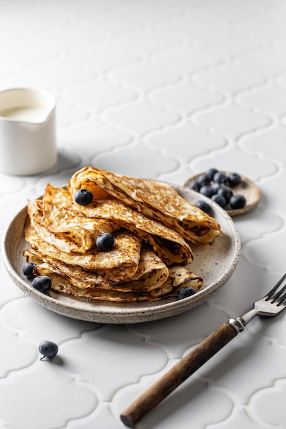 Deliciosos crepes caseros en plato de cerámica con bayas sobre fondo de azulejo blanco para maslenitsa