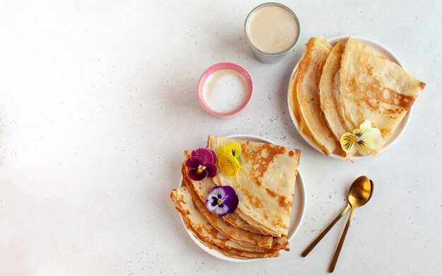 Deliciosos crepes en platos, decorados con flores y tazas de café.