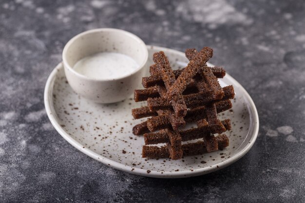 Deliciosos croutons escuros empilhados uns sobre os outros, servidos com molho de alho aromático.