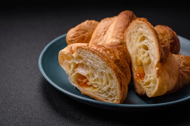 Deliciosos crujientes croissants dulces horneados con relleno en un plato de cerámica