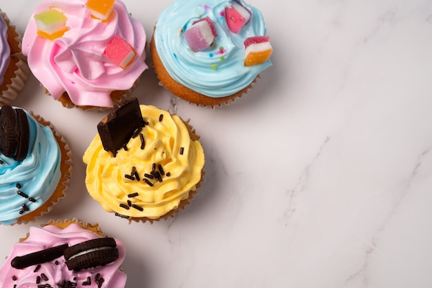 Deliciosos cupcakes caseros con crema de colores y cobertura con dulces y galletas de chocolate