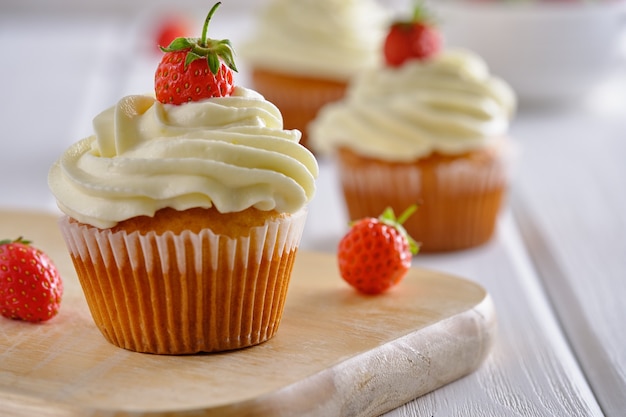 Deliciosos cupcakes con fresas y crema suave sobre un fondo blanco de cerca