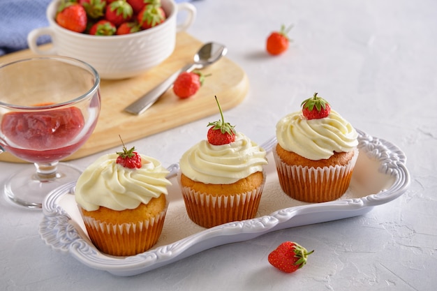 Deliciosos cupcakes con fresas y crema suave sobre un fondo blanco.