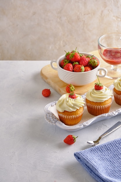 Foto deliciosos cupcakes con fresas y crema suave sobre un fondo blanco.