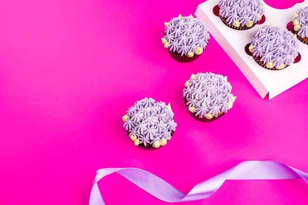 Deliciosos cupcakes shawn con crema cuajada en forma de flores sobre un fondo rosa.